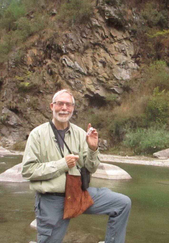 Gard W. Otis, Professor Emeritus, University of Guelph standing near a stream