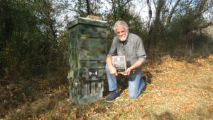 David Parker kneeling at beehive with citation